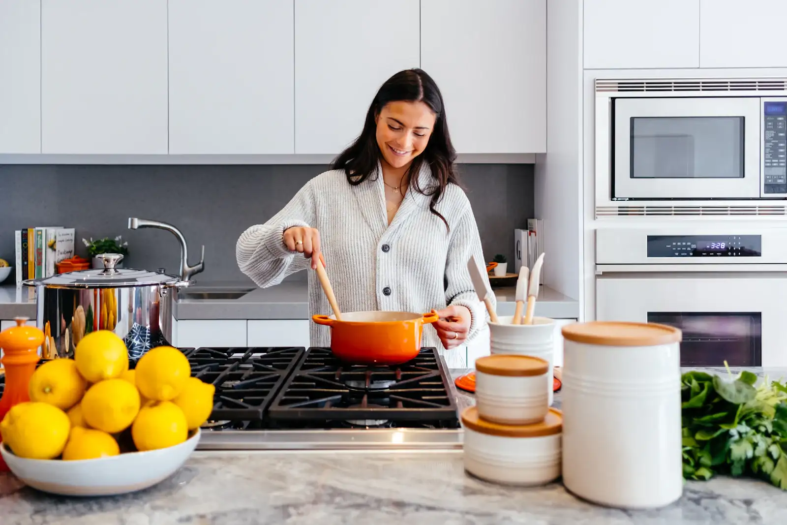 A cook at a gas range in a white kitchen with marble counters. Shown on the homepage for Hinsdale, IL.